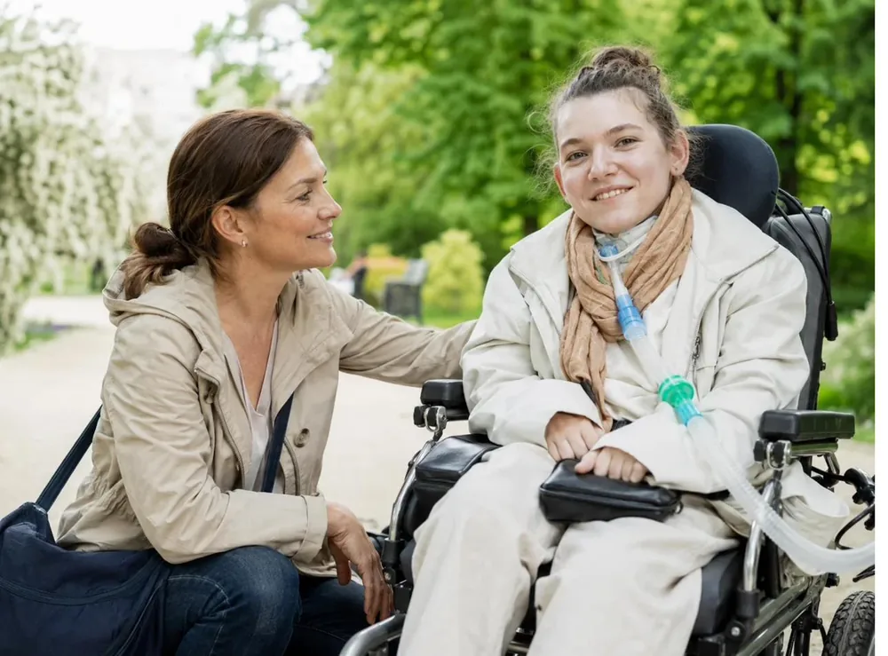 Une jeune fille en situation de handicap et son auxiliaire de vie échangent un sourire complice lors d'une sortie