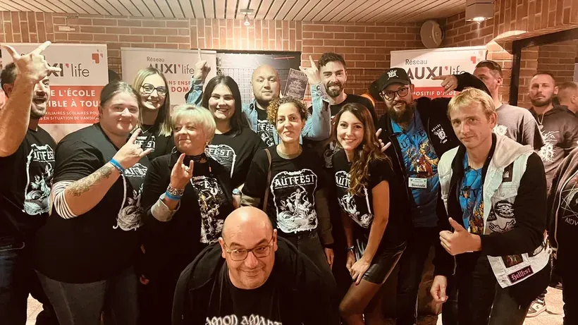 Les équipes et bénévoles de l'AÜTFËST réunis devant les stands du Réseau AUXI'life, partenaire principal du festival metal au profit de l'autisme