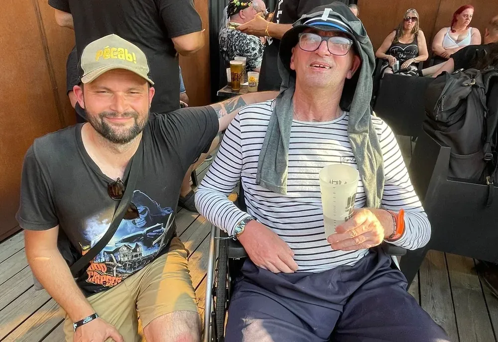 Un homme en fauteuil roulant partage un moment convivial avec son accompagnant lors d'une sortie, reflet de l'accompagnement du Réseau AUXI'life au-delà du domicile
