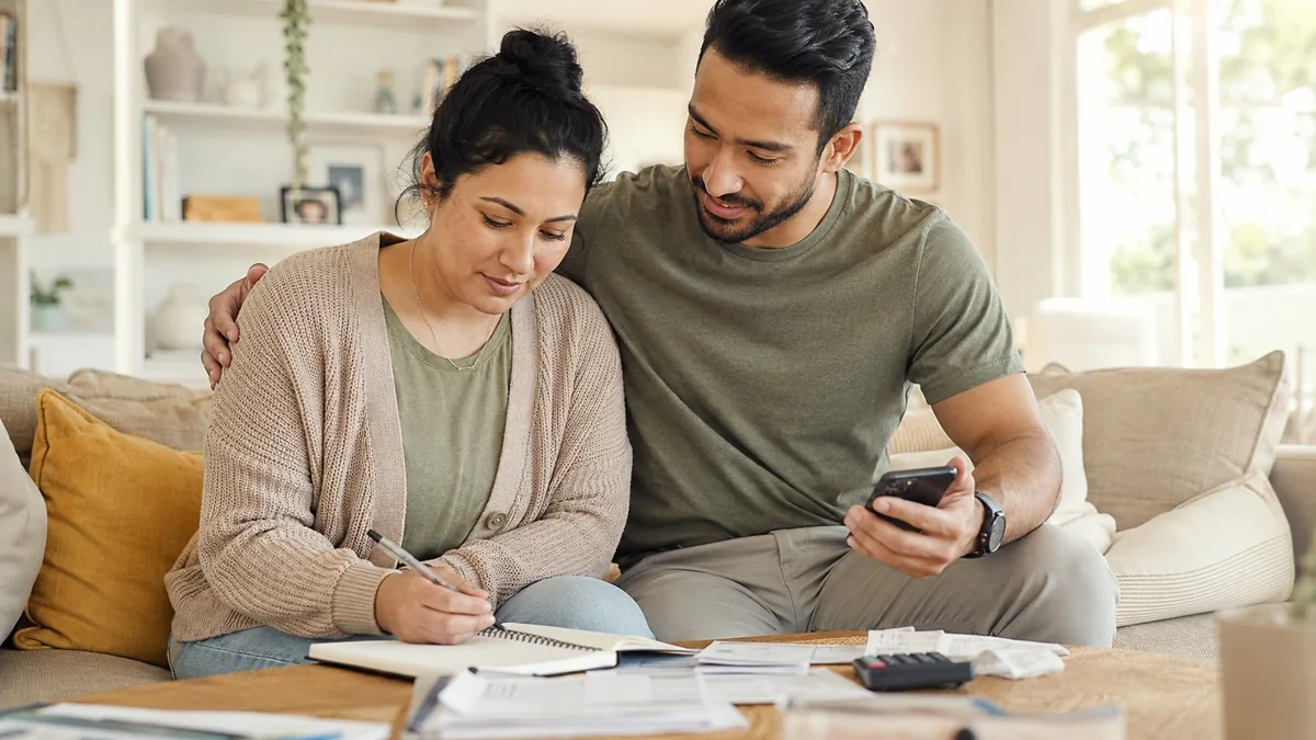 Un couple organise à domicile les démarches et le budget liés au handicap, papiers et calculatrice sur la table